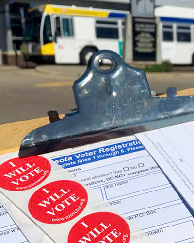 voter pledge card and stickers on clipboard with bus in background