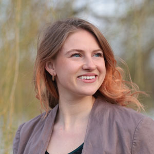 Photo of Katie Cashman, a white woman with strawberry blond hair wearing a light purple jacket