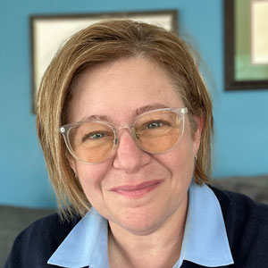 A photo of Lona Dallessandro, a white woman with clear glasses and chin-length blond hair
