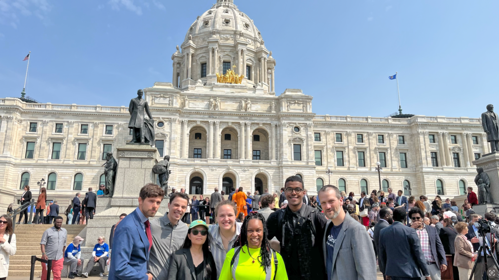 Advocates from Move Minnesota Action and RMI smile in front of the Minnesota state capitol after an event in 2023