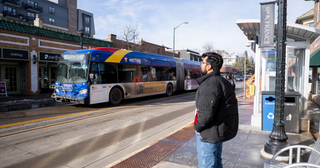 A man on the street watches a BRT bus arrive